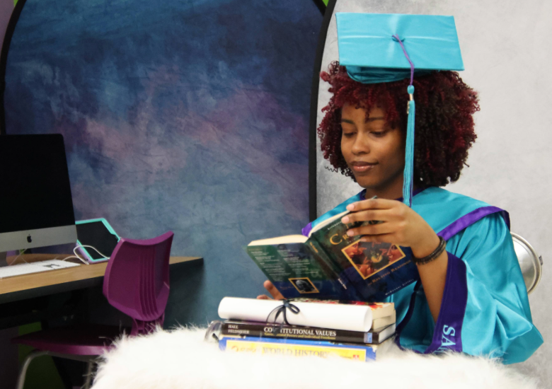 A female student wearing graduation regalia for a senior portrait sitting.